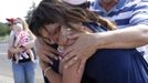 Elizabeth Sumrall, 23, is embraced in front of a memorial for victims behind the theater where a gunman opened fire on moviegoers in Aurora, Colorado July 21, 2012. James Holmes, who is accused in a shooting rampage at a Denver-area premiere of the new "Batman" film, received a high volume of deliveries at work and home over the past four months, police said, parcels they believe contained ammunition and possibly bomb-making materials. Aurora Police Chief Dan Oates revealed the shipments as local and federal authorities worked to make safe suspect Holmes' apartment, which was found to be booby-trapped with sophisticated explosives following the massacre at a multiplex theatre several miles away. REUTERS/Shannon Stapleton (UNITED STATES - Tags: CRIME LAW) Published: Čec. 21, 2012, 11:45 odp.