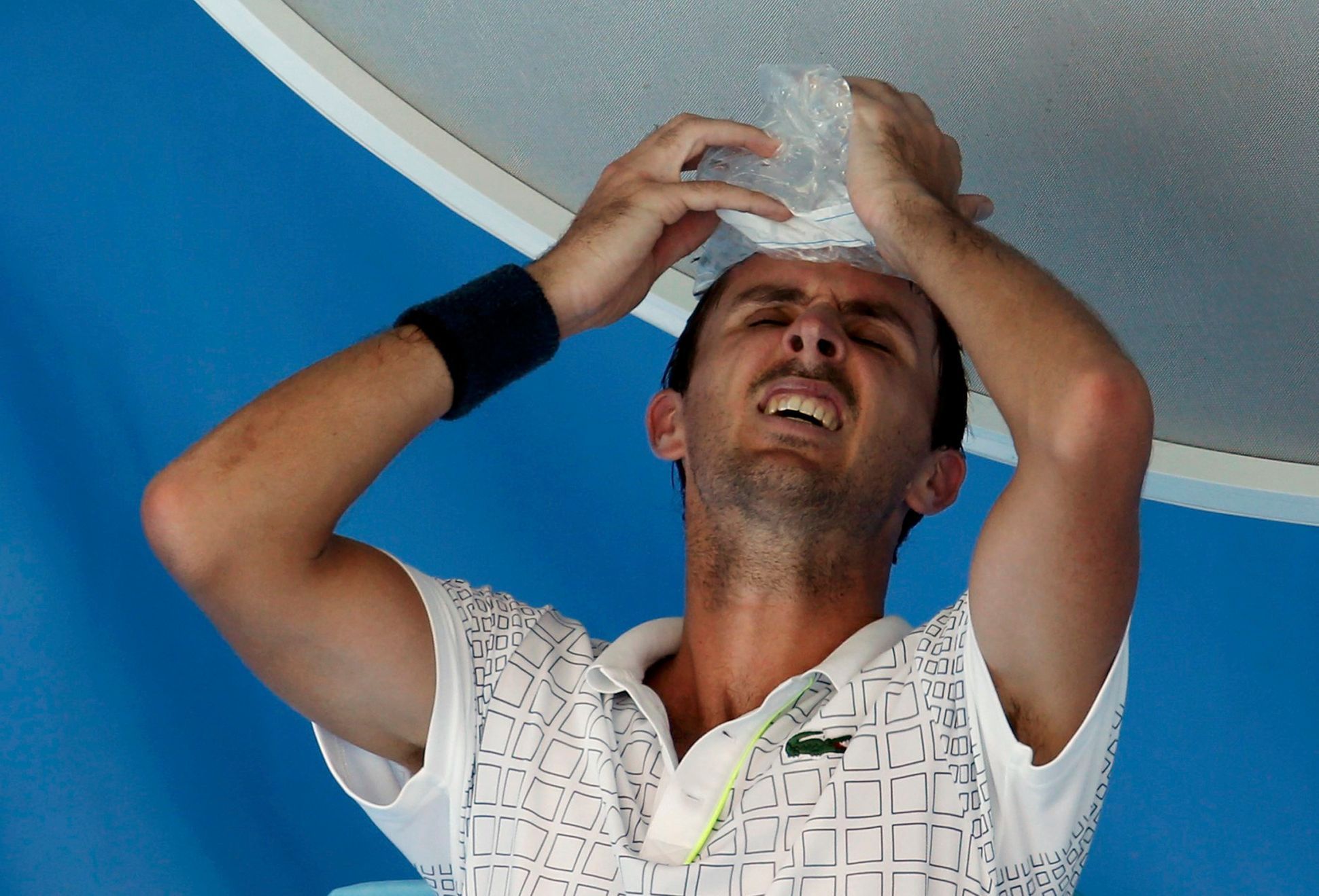 Roger-Vasselin of France holds a bag of ice to his head during a break in play in his men's singles match against Anderson of South Africa at Australian Open 2014 tennis tournament in Melbourne