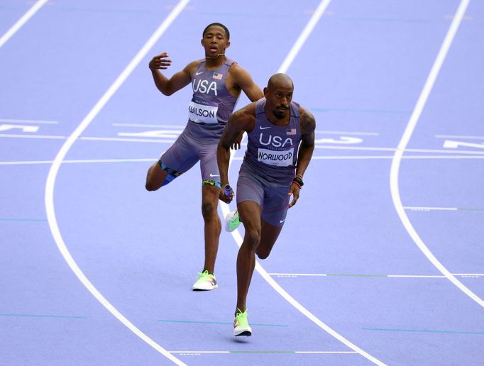 Americký atlet Quincy Wilson předává Vernonu Norwoodovi v závodě štafet na 4x400 m na OH 2024 v Paříži