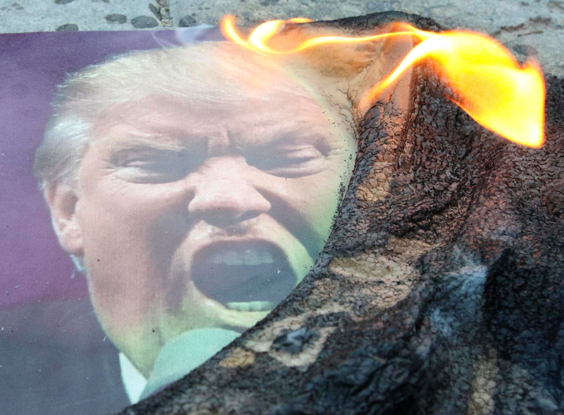Zapálená fotografie Trumpa na demonstraci proti náletům v Simferopolu na Krymu.