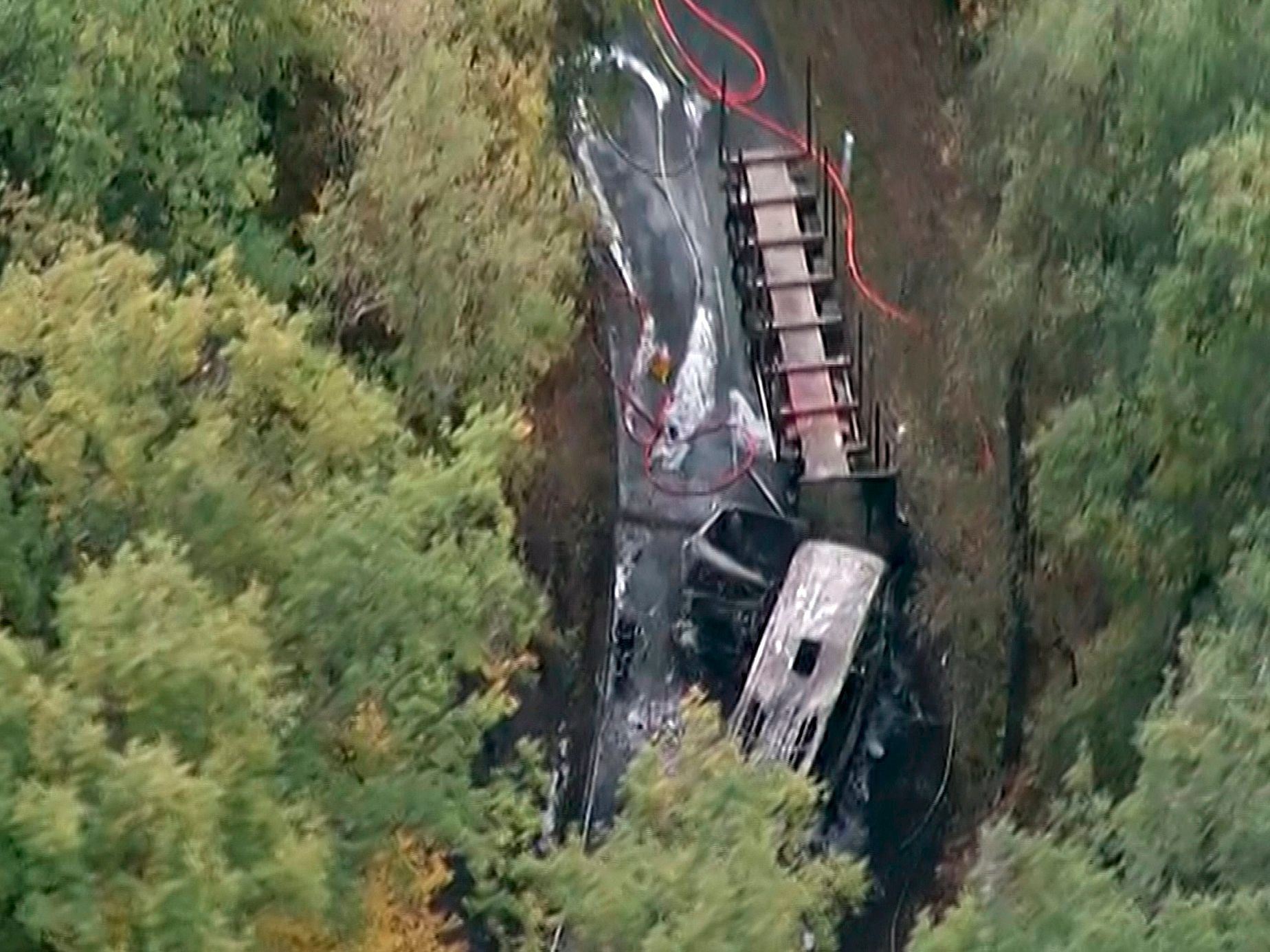 Fotografie, pořízená z videozáznamu francouzské televize. Na snímku jsou vidět shořelé vraky kamionu a autobusu.