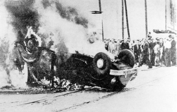 Lidé sledují hořící auto člena vládnoucí komunistické vlády, které bylo zapáleno během demonstrací. Záběr z povstání 17. června 1953 ve Východním Berlíně.