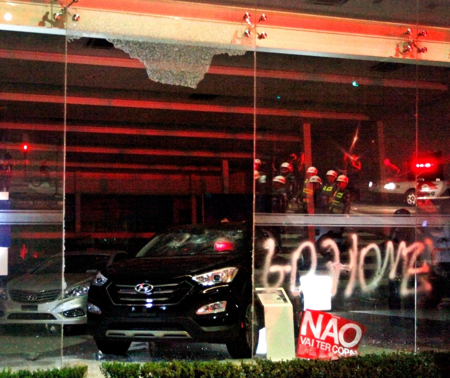 The glass door and some cars which were vandalized are seen in a vehicle store during a protest against 2014 World Cup in Sao Paulo