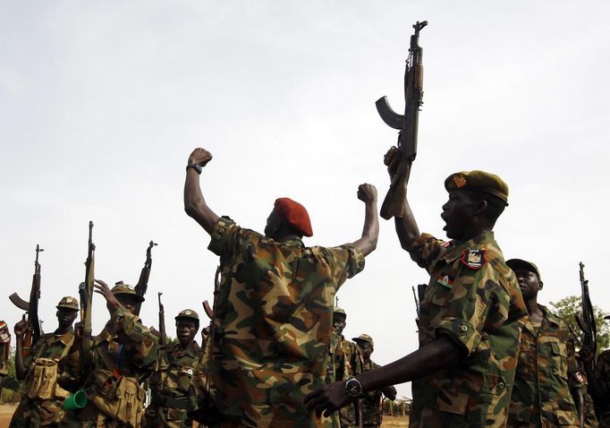 South Sudan's SPLA soldiers hold up their weapons as they shout at a military base in Bentiu