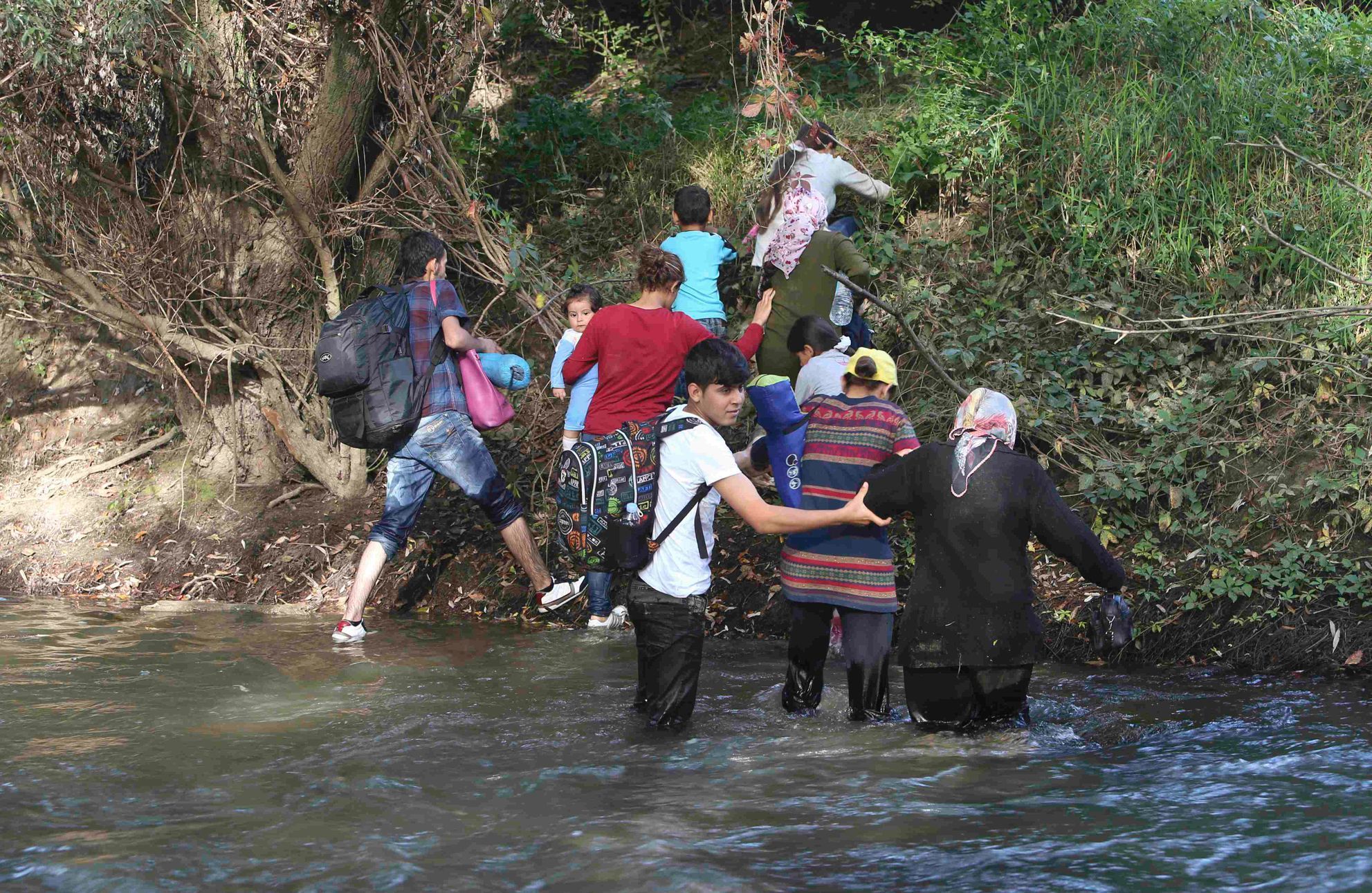Uprchlíci překračují řeku Sutla na slovinské hranici.