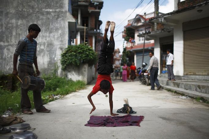 Gchan Choudhary, 17, plays a drum as his younger brother Drumpal Choudhary, 11, performs trick at the streets of Kathmandu August 15, 2012. Gchan and Drumpal, together with their sister, Shivani, came to Kathmandu from India 5 years ago, earn their living by performing tricks on the streets of Kathmandu. According to Drumpal, Shivani's older brother, they earn around $10 a day by performing tricks, which is not enough to feed their 10-member family living together in a small hut without a proper toilet or any basic needs. REUTERS/Navesh Chitrakar (NEPAL - Tags: SOCIETY POVERTY IMMIGRATION) Published: Srp. 15, 2012, 4:14 odp.