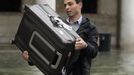 A man carries his luggage at the flooded St. Mark square during a period of seasonal high water in Venice November 1, 2012. The water level in the canal city rose to 140 cm (55 inches) above normal, according to the monitoring institute. REUTERS/Manuel Silvestri (ITALY - Tags: ENVIRONMENT SOCIETY) Published: Lis. 1, 2012, 1:20 odp.