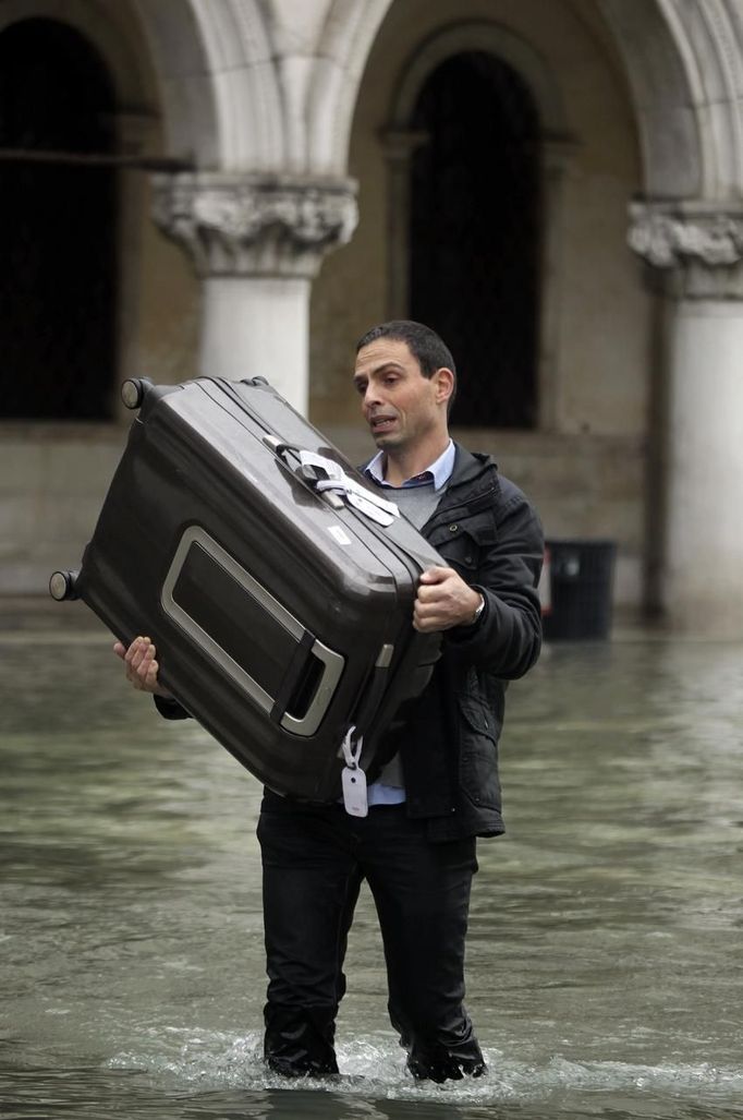 A man carries his luggage at the flooded St. Mark square during a period of seasonal high water in Venice November 1, 2012. The water level in the canal city rose to 140 cm (55 inches) above normal, according to the monitoring institute. REUTERS/Manuel Silvestri (ITALY - Tags: ENVIRONMENT SOCIETY) Published: Lis. 1, 2012, 1:20 odp.