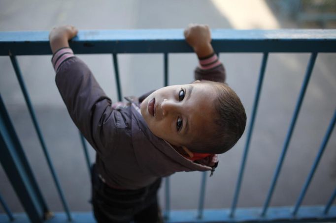 A displaced Palestinian boy, who fled his family's house, looks up as he stays with his family at a United Nations-run school in Gaza City November 20, 2012. From the sandy expanses of the northern Gaza Strip, Palestinian families are fleeing their homes destroyed by airstrikes, but refuse to blame the Hamas rocket crews who draw Israeli fire. REUTERS/Ahmed Jadallah (GAZA - Tags: MILITARY CONFLICT POLITICS) Published: Lis. 20, 2012, 7:52 dop.