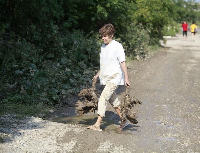 Žena odnáší mrtvou drůběž.