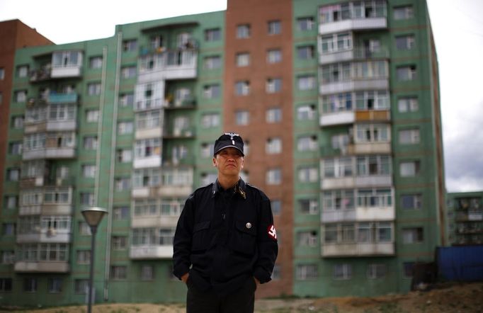 Ariunbold Altankhuum, founder of Mongolian neo-Nazi group Tsagaan Khass, stands next to a statue of Chingunjav, a Mongolian national hero (unseen), in Ulan Bator June 22, 2013. The group has rebranded itself as an environmentalist organisation fighting pollution by foreign-owned mines, seeking legitimacy as it sends Swastika-wearing members to check mining permits. Over the past years, ultra-nationalist groups have expanded in the country and among those garnering attention is Tsagaan Khass, which has recently shifted its focus from activities such as attacks on women it accuses of consorting with foreign men to environmental issues, with the stated goal of protecting Mongolia from foreign mining interests. This ultra-nationalist group was founded in the 1990s and currently has 100-plus members. Picture taken June 22, 2013. REUTERS/Carlos Barria (MONGOLIA - Tags: SOCIETY POLITICS BUSINESS EMPLOYMENT ENVIRONMENT) ATTENTION EDITORS: PICTURE 01 OF 25 FOR PACKAGE 'MONGOLIA'S ENVIRONMENTAL NEO-NAZIS'. TO FIND ALL IMAGES SEARCH 'TSAGAAN KHASS' Published: Čec. 2, 2013, 9:57 dop.