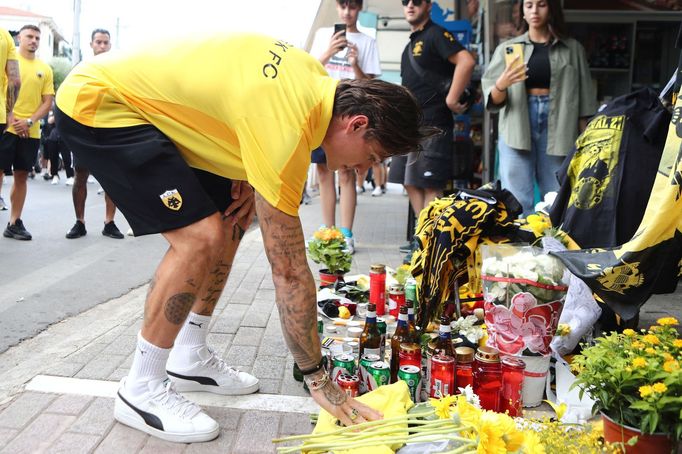 An AEK Athens club soccer player places flowers outside Agia Sophia Stadium, the home stadium of AEK Athens soccer team following clashes between soccer fans, in Athens,