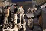 Lybijští vojáci stojí na troskách rozbombardované části Kaddáfího sídla Báb al-Azízíja.