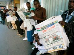 Lidé pročítají noviny, které uveřejnily předběžné výsledky voleb