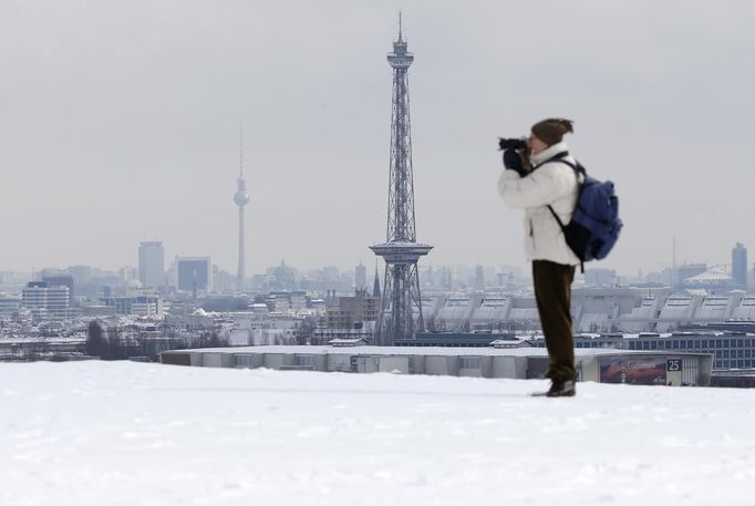 A man takes pictures of the snow covered skyline with the radio transmission tower (R) and the TV tower (L) in Berlin, March 12, 2013. REUTERS/Fabrizio Bensch (GERMANY - Tags: ENVIRONMENT) Published: Bře. 12, 2013, 12:12 odp.