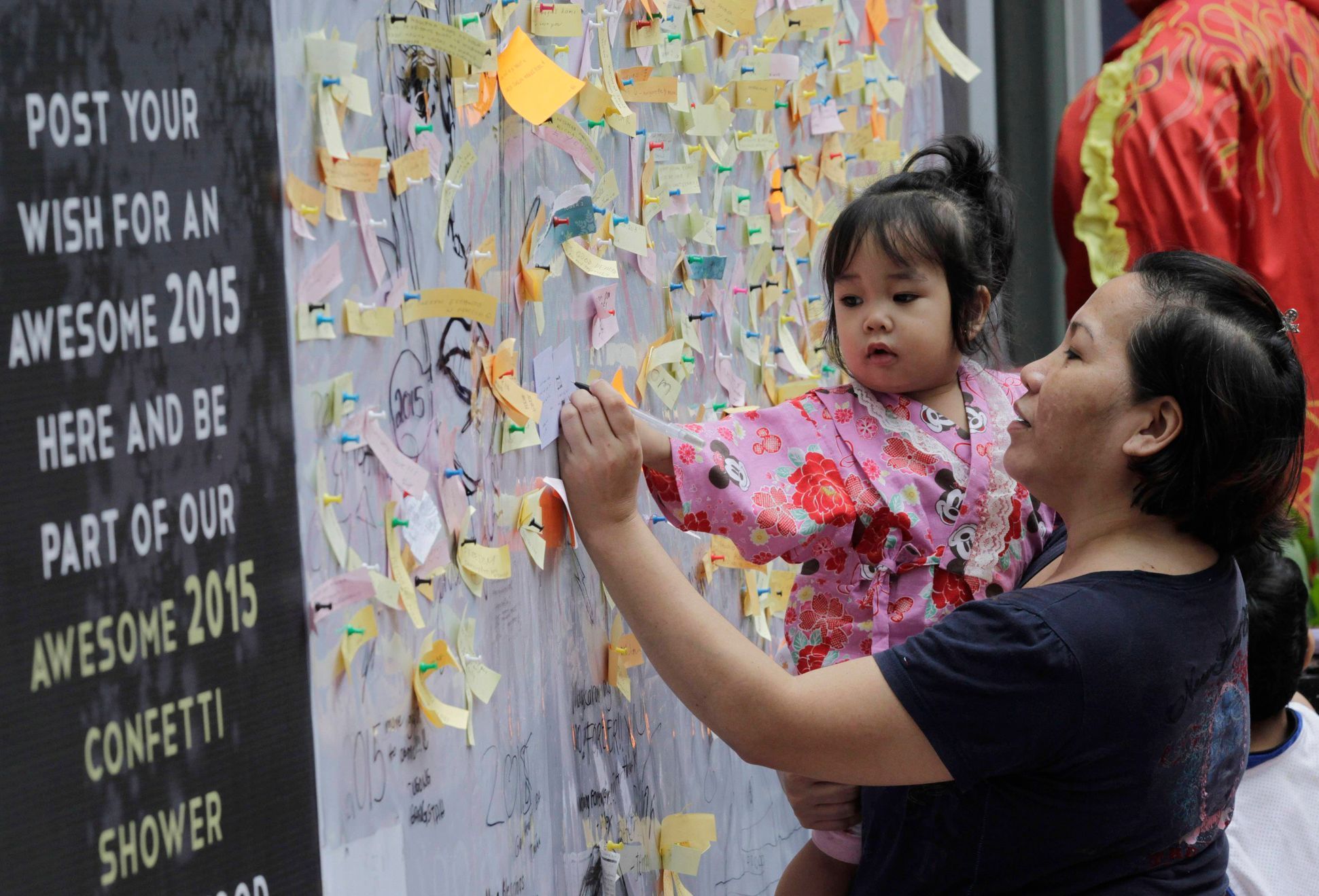 Woman writes her New Year wishes on a wishing wall display at a mall in Quezon city