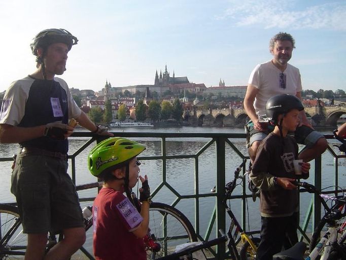 After the finish line. Bikers enjoying snacks (and beer) by the river with the view of Prague Castle and Charles Bridge in the background.