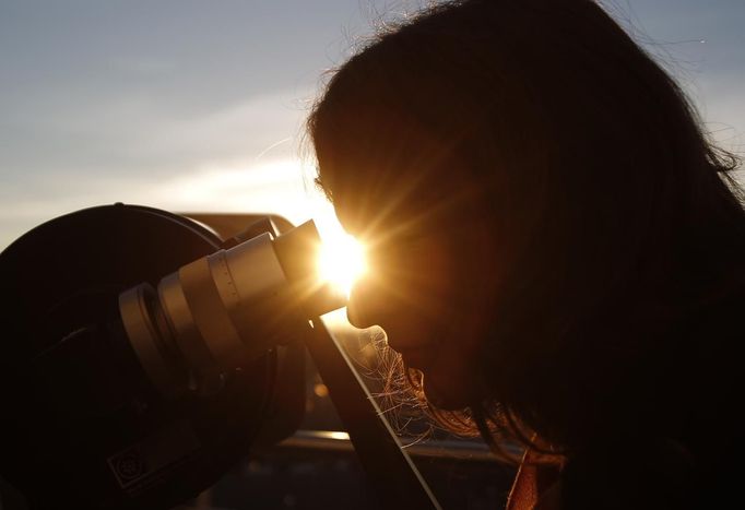 A woman looks through a telescope as the planet Venus transits across the sun during sunrise in Vienna, June 6, 2012. Venus made a slow transit across the face of the sun on Wednesday, the last such passing that will be visible from Earth for 105 years. REUTERS/Lisi Niesner (AUSTRIA - Tags: ENVIRONMENT SCIENCE TECHNOLOGY) Published: Čer. 6, 2012, 4:52 dop.