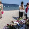 Ženy se modlí poblíž hromady květin na pláži před hotelem Imperial Marhaba.
