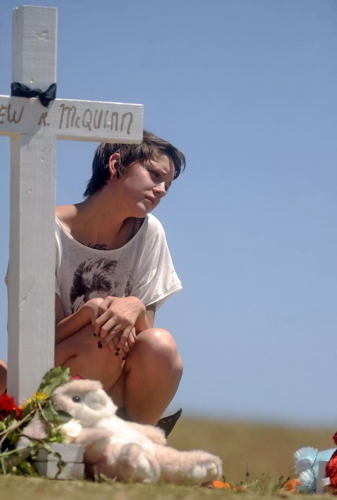 An unidentified woman pauses by a cross at a memorial for victims in Aurora, Colorado July 22, 2012. The makeshift memorial was erected behind the theater where a gunman opened fire on moviegoers during a midnight premiere showing of The Dark Knight on July 20, 2012. Residents of a Denver suburb mourned their dead on Sunday from a shooting rampage by a "demonic" gunman who killed 12 people and wounded 58 after opening fire at a cinema showing the new Batman movie. President Barack Obama headed to Aurora, Colorado, on Sunday to meet families grieving their losses Friday's mass shooting that has stunned the nation and rekindled debate about guns and violence in America. REUTERS/ Evan Semon (UNITED STATES - Tags: CRIME LAW SOCIETY) Published: Čec. 22, 2012, 11:24 odp.