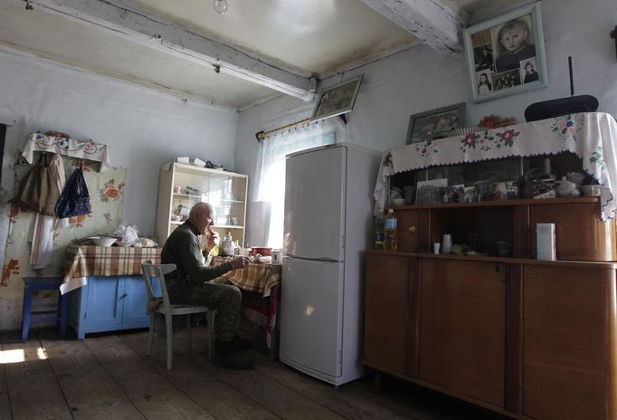 Villager Shamianok has breakfast in his house at abandoned village of Tulgovichi