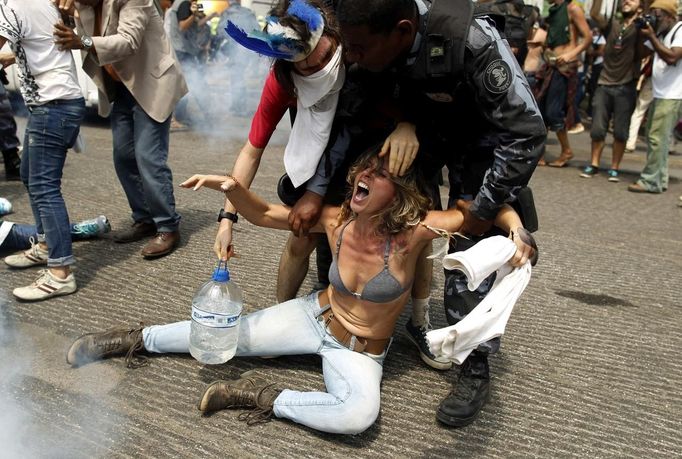 A supporter of a native Indian community living at the Brazilian Indian Museum is dragged by a military officer during a protest against the community's eviction in Rio de Janeiro, March 22, 2013. Brazilian military police took position early morning outside the abandoned museum, where the community of around 30 native Indians have been living in since 2006. The community was ordered to leave the museum in 72 hours by court officials since last week, local media reported. Most of the Indians later left the museum after making a deal with the authorities. REUTERS/Pilar Olivares (BRAZIL - Tags: POLITICS CIVIL UNREST SOCIETY) Published: Bře. 22, 2013, 7:04 odp.