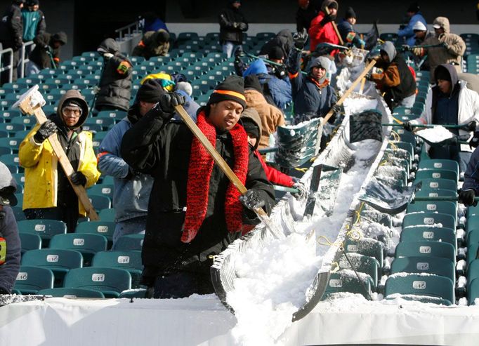 Úklid sněhu ze sedaček stadionu Philadelphia Eagles ve Philadelphii. Zápas nakonec musel být stejně odložen.