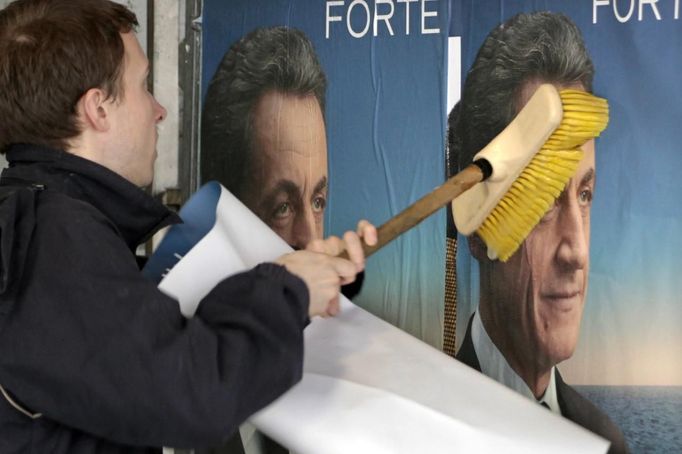 A UMP party activist glues election campaign posters in support of Sarkozy, France's President and UMP party candidate for the 2012 French presidential election, on an official board in Paris