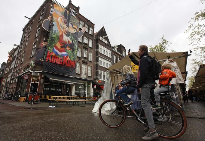 A family looks at a giant poster depicting a caricature of Crown Prince Willem-Alexander and Princess Maxima in Amsterdam April 29, 2013. The Netherlands is preparing for Queen's Day on April 30, which will also mark the abdication of Queen Beatrix and the investiture of her eldest son Willem-Alexander. REUTERS/Cris Toala Olivares (NETHERLANDS - Tags: ROYALS POLITICS) Published: Dub. 29, 2013, 9:22 dop.