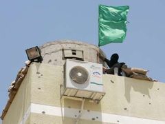 Ozbrojenec Hamásu vztyčuje vlajku tohoto islamistického hnutí na budově bezpečnostních složek v Gaze