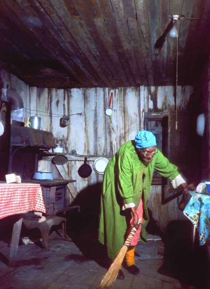 Poor does not mean untidy. An old woman is sweeping her shack with extreme care