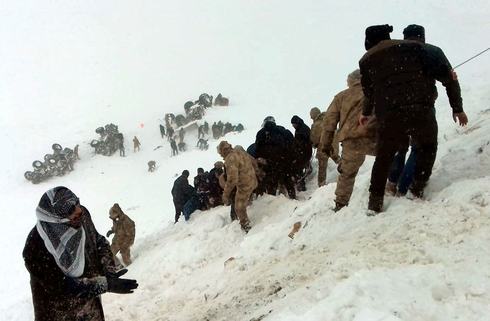 Turečtí vojáci a místní se snaží pomoci lidem zavaleným lavinou.