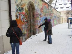 Zahraniční turisté u Lennonovy zdi. V mnoha bedekrech se o ní píše.