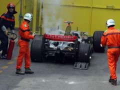 Hasiči kontrolují kouřící McLaren finského pilota Kimi Räikkönena.