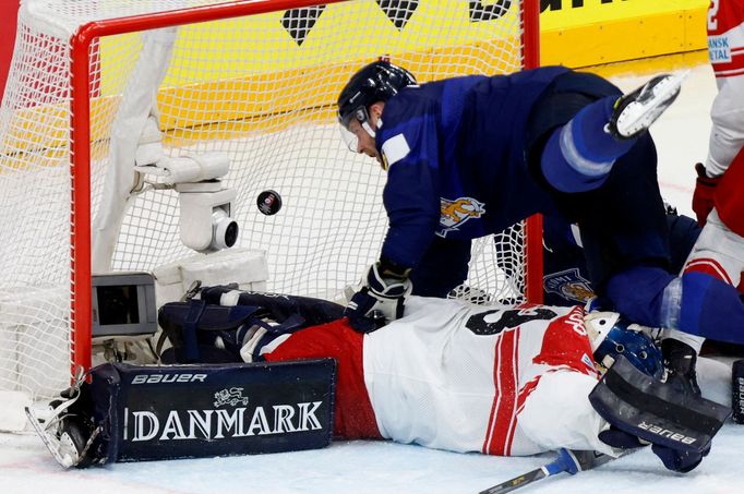 Finský hokejista Iiro Pakarinen se pokouší dostat puk za dánského brankáře Mathiase Seldrupa