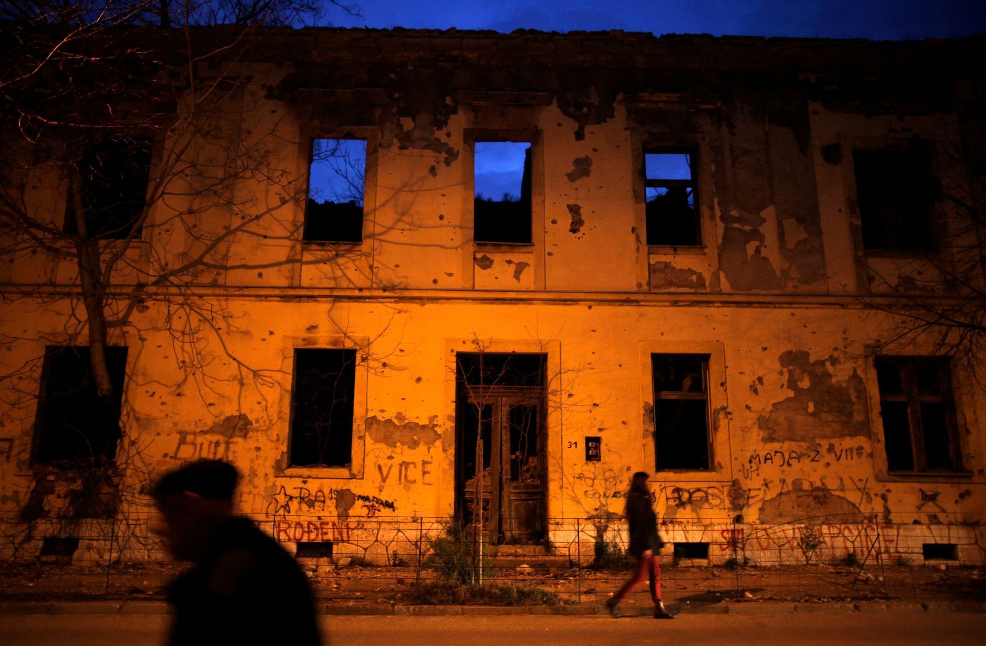 File photo of people walking next to a destroyed building in Mostar