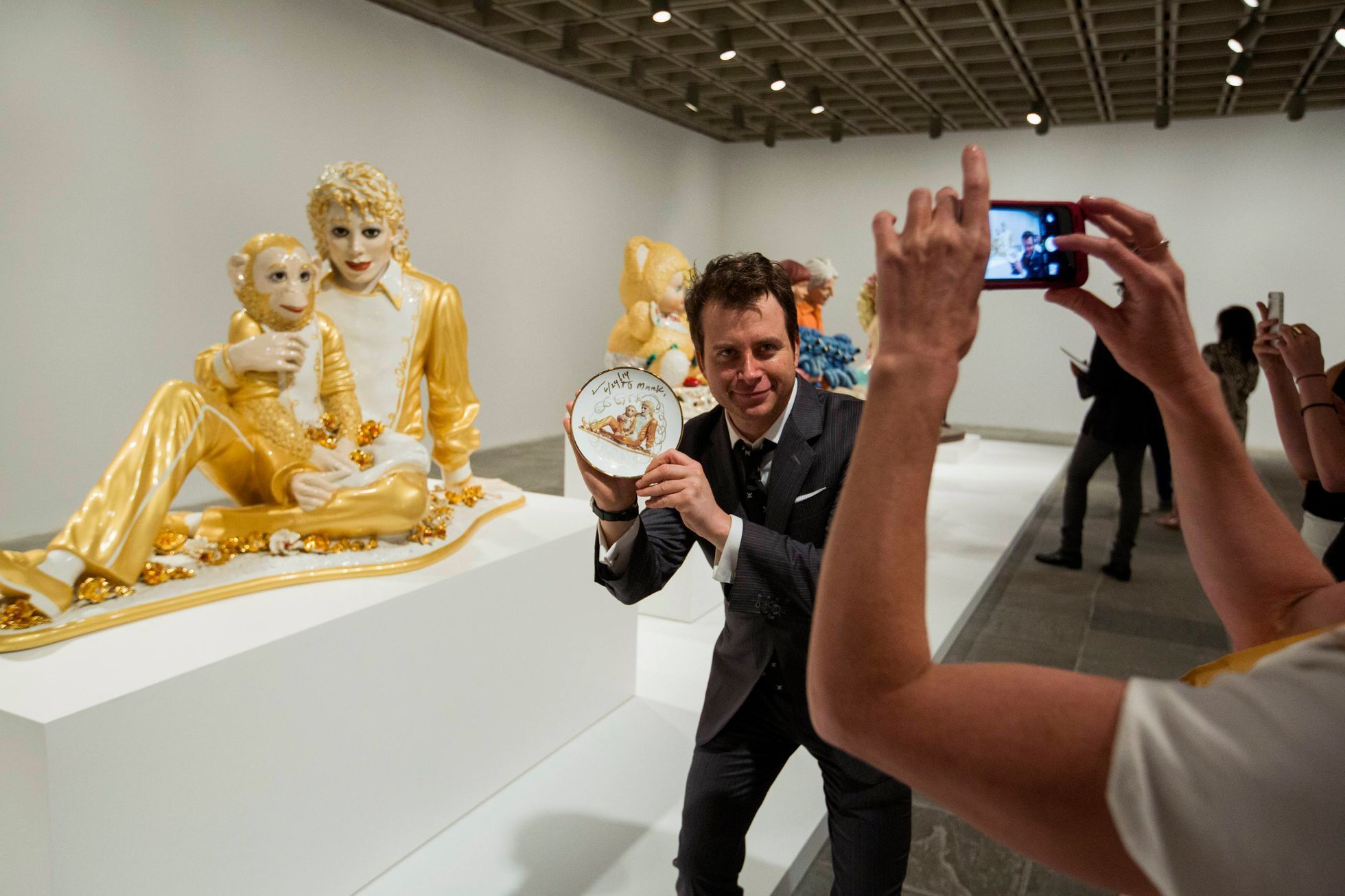 A man holds a signed plate before the opening of a Jeff Koons retrospective at the Whitney Museum of American Art in New York