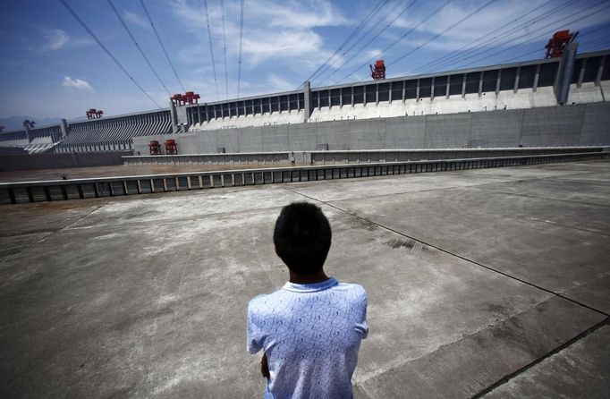 A man stands next to the Three Gorges dam in Yichang, Hubei province in this August 9, 2012 file photo. China relocated 1.3 million people during the 17 years it took to complete the Three Gorges dam. Even after finishing the $59 billion project last month, the threat of landslides along the dam's banks will force tens of thousands to move again. It's a reminder of the social and environmental challenges that have dogged the world's largest hydroelectric project. While there has been little protest among residents who will be relocated a second time, the environmental fallout over other big investments in China has become a hot-button issue ahead of a leadership transition this year. Picture taken on August 9, 2012. To match story CHINA-THREEGORGES/ REUTERS/Carlos Barria/Files(CHINA - Tags: POLITICS ENVIRONMENT BUSINESS ENERGY) Published: Srp. 22, 2012, 8:38 odp.