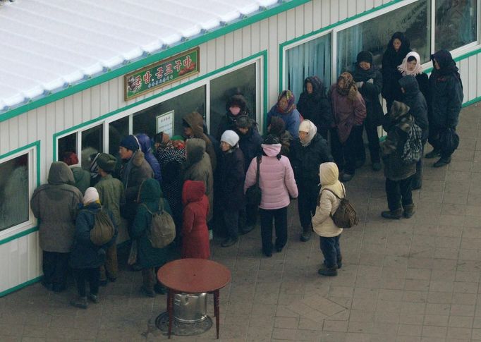 North Koreans gather under a sign that advertises cooked chestnuts and sweet potatoes in Pyongyang, in this photo taken by Kyodo December 12, 2012. Isolated and impoverished North Korea launched its second long- range rocket of 2012 on Wednesday and may have finally succeeded in putting a satellite into space, the stated aim of what critics say is a disguised ballistic missile test. REUTERS/Kyodo (NORTH KOREA - Tags: MILITARY POLITICS) FOR EDITORIAL USE ONLY. NOT FOR SALE FOR MARKETING OR ADVERTISING CAMPAIGNS. THIS IMAGE HAS BEEN SUPPLIED BY A THIRD PARTY. IT IS DISTRIBUTED, EXACTLY AS RECEIVED BY REUTERS, AS A SERVICE TO CLIENTS. MANDATORY CREDIT. JAPAN OUT. NO COMMERCIAL OR EDITORIAL SALES IN JAPAN. YES