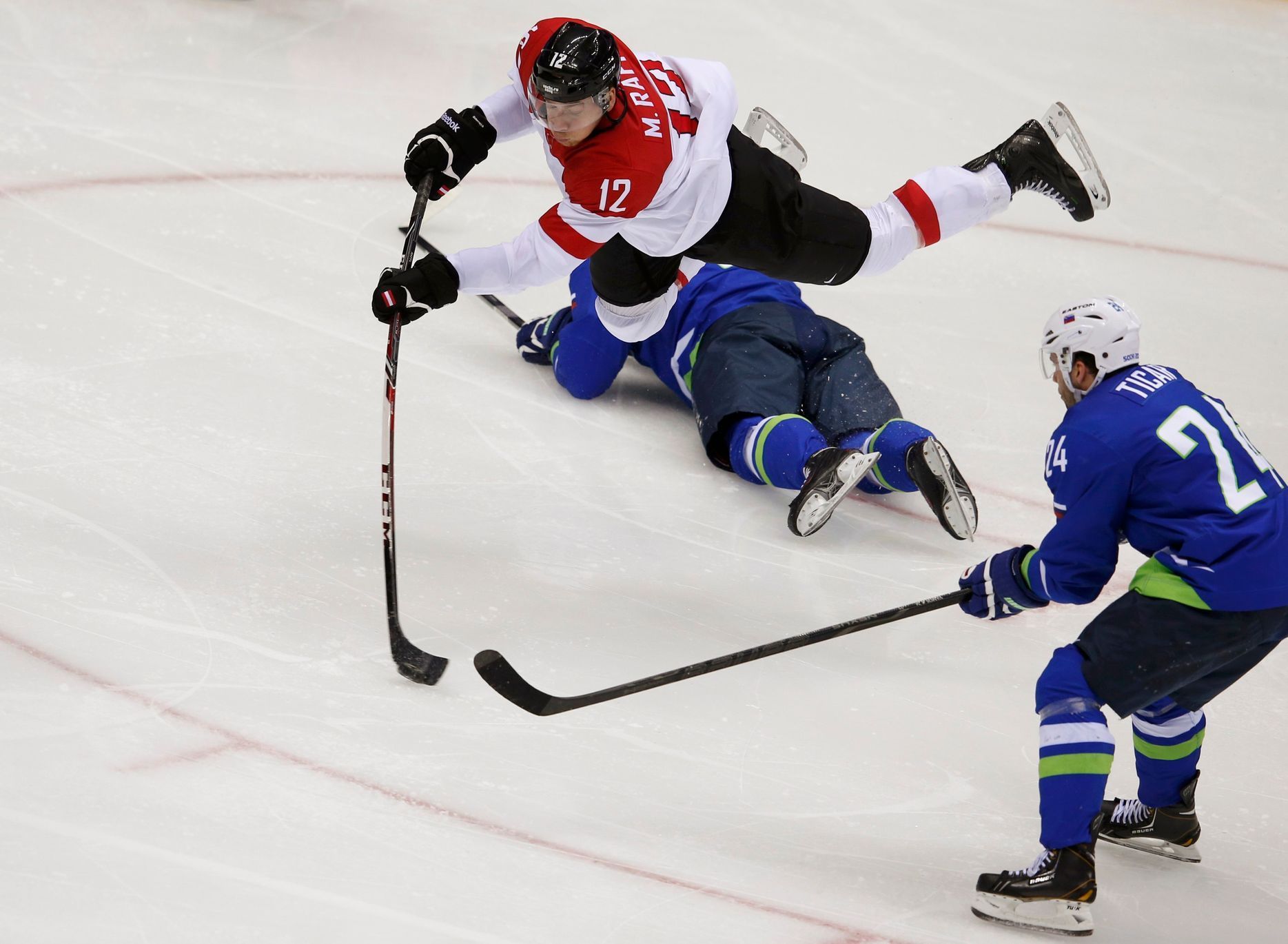 Austria's Michael Raffl flies through the air after tripping over Slovenia's Ziga Pavlin during the second period of their men's ice hockey playoffs qualification game at the 2014 Sochi Winter Olympic