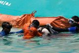 Potápěči nakládají tělo utonulého do igelitového vaku. Záchranáři se obávají, že převrácená loď se stala masovým hrobem většiny z více než osmi set cestujících.