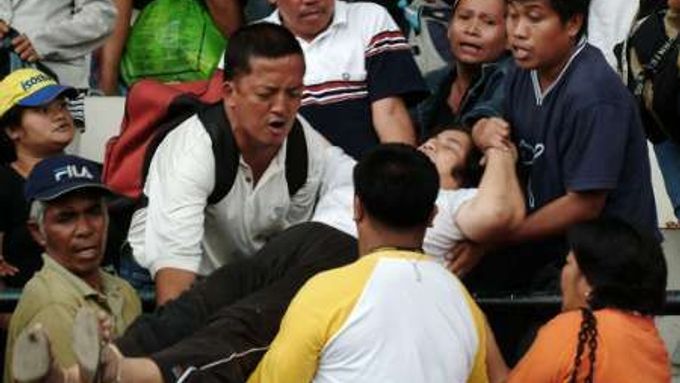 Filipínci vynášejí ze stadionu zraněnou ženu.