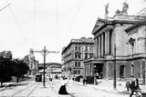 Průhled Wilsonovou ulicí s budovou Nového německého divadla (Státní opera), dnešní Wilsonovo nádraží v pozadí. Snímek pořízen mezi lety 1910 a 1915.