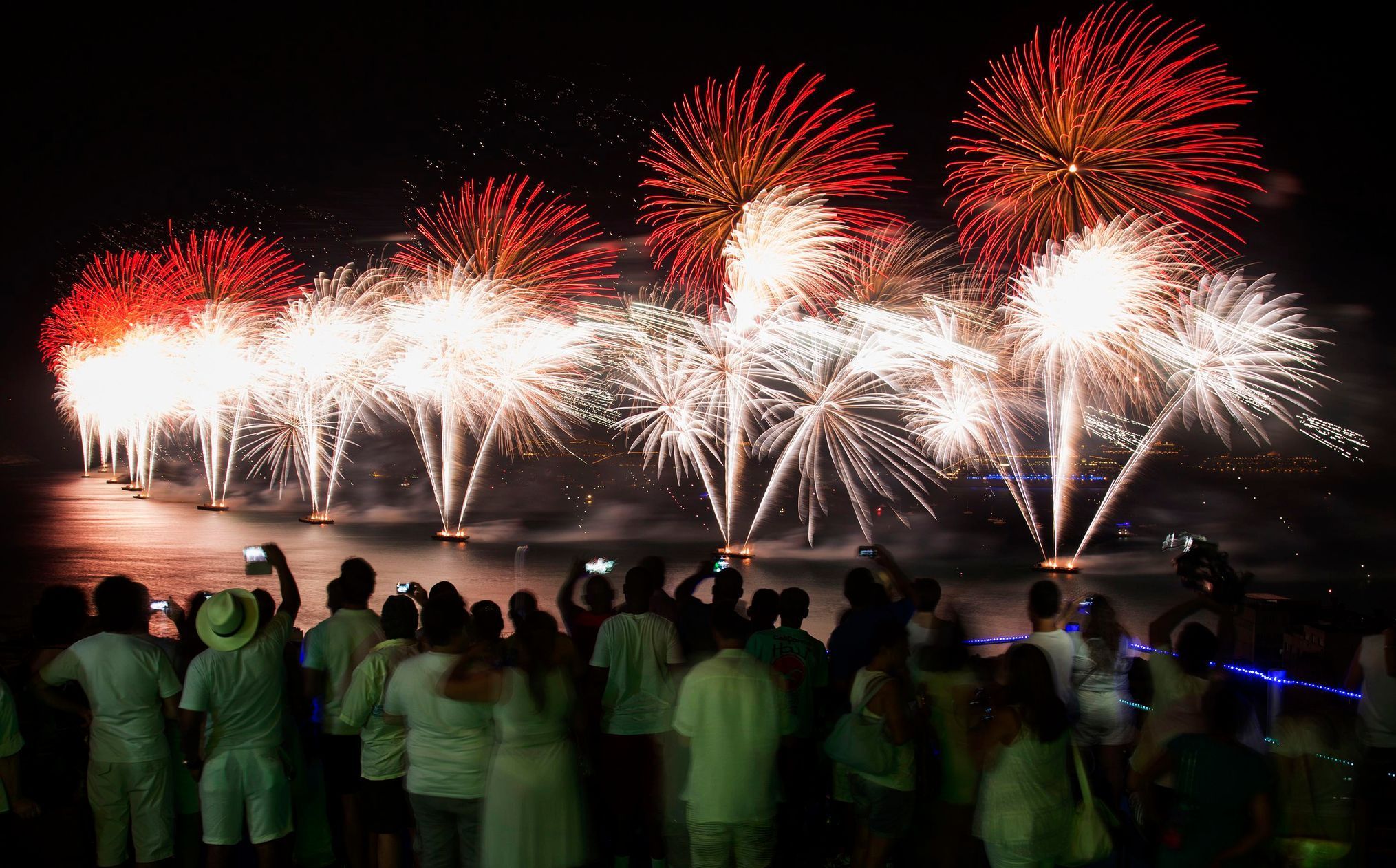 People watch fireworks exploding over Copacabana beach during New Year celebrations at the Pavao Pavaozinho slum in Rio de Janeiro