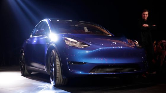 Tesla Model Y při premiéře spolu s Elonem Muskem v pozadí.