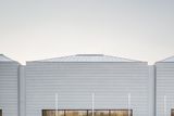 Bílou, betonovou kostku se sedlovou střechou a sportovišti navrhlo studio bod architekti, které je autorem třeba nové radnice pro Prahu 7 nebo rekonstrukce hospody v Máslovicích.