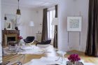 Elegantní obývací pokoj s parketovou podlahou je vybaven solitérními designovými kousky nábytku. Místo koberců jsou položeny bílé kůže.