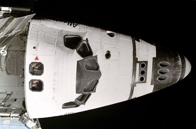 Listopad 1995. Pět astronautů mise STS-74 vykukuje z okének raketoplánu Atlantis při průletu kolem ruské vesmírné stanice Mir. Posádku tvořili (odshora dolů): velitel letu Kenneth Cameron, specialista Jerry Ross, pilot James Halsell Jr. a specialisté William McArthur a Chris Hadfield - ten byl z Kanady.