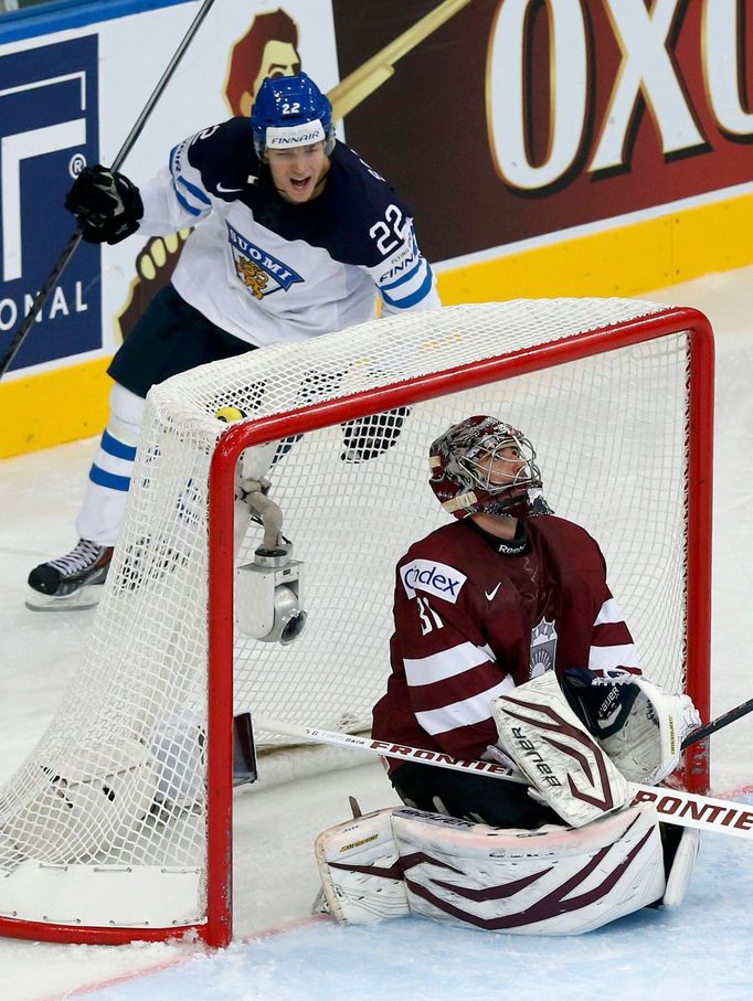 Finland's Miikka Salomaki (top) celebrates his goal as Latvia's goalie Edgars Masalskis reacts during their men's ice hockey World Championship group B game at Minsk Aren