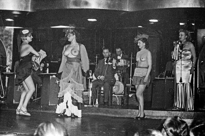 Diváci sledují vystoupení čtyř striptýzových tanečnic na pódiu nočního klubu v hamburském Reeperbahnu, 50. léta 20. století.